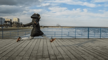 Kid running on a pier in a winter jacket happily